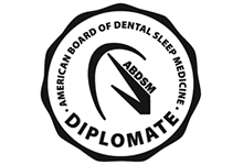 The image is a logo of the American Board of Dental Sleep Medicine, featuring a seal-like design with text that includes American Board of Dental Sleep Medicine and DIPLOMATE.