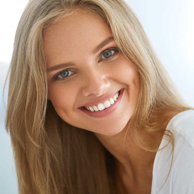 A young woman with blonde hair and a radiant smile, looking directly at the camera.